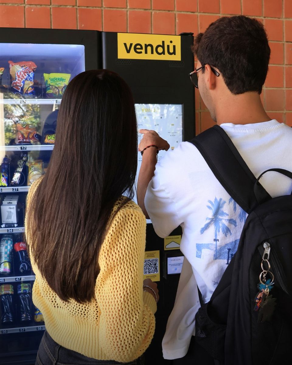 Two students choosing snacks on the touchscreen of a vendu. vending machine at a university in Caracas, Venezuela